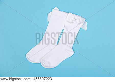 High White Children's Socks With Big Bows For Festive Clothes On A Blue Background Top View