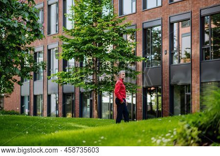 Businessman Walking In Park Near Office Buliding During Break, Work Life Balance Concept.