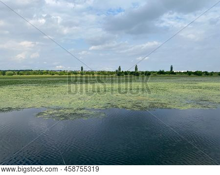 Landscape View Of Lake With Vegetation On It And Sky With Clouds Reflected In The Water