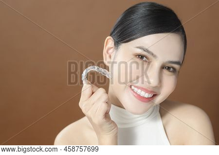 A Young Woman With Beautiful Teeth Is Holding Invisalign, Healthy Dental Concept