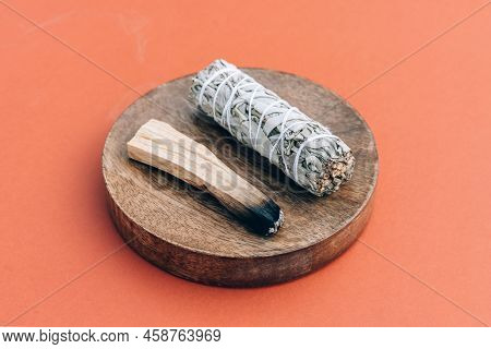 Burning Incense Bundle. White Sage And Burning Palo Santo Stick On Wooden Stand Over Orange Brown Ba