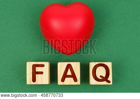 On A Green Surface, A Red Heart And Wooden Cubes With The Inscription - Faq. Close Up