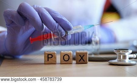 Close-up Of Word Pox Collected Of Wooden Cubes In Row. Doctor Holding Injection Syringe In Hand. Vir