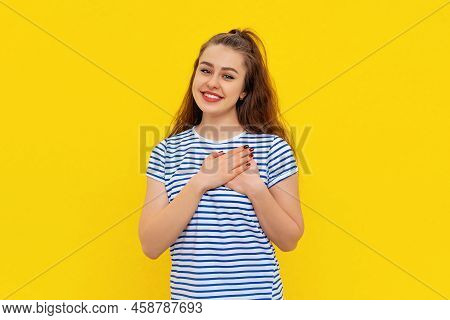 Portrait Of Peaceful, Dear Girl Holding Hands At Chest Close To Heart, Smiling Grateful, Show Apprec