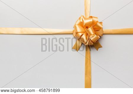 Top View Of Gold Ribbon Rolled And Yellowbow Isolated On Colored Background. Flat Lay With Copy Spac