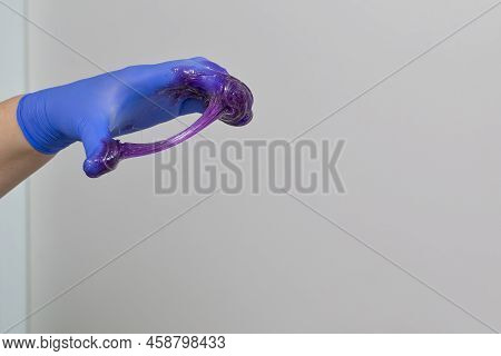 Beautician Hands In Gloves With Liquid Purple Wax Composite During Waxing Or Sugaring Proceedure In