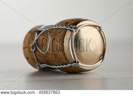 Cork Of Sparkling Wine And Muselet Cap On White Wooden Table, Closeup