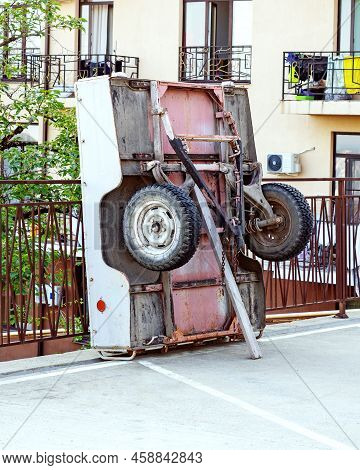 Car Trailer. Overturned Cart. Overturned Wheelbarrow. An Overturned Car Trailer Stands At The Fence 