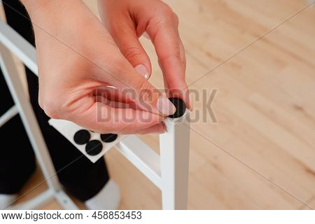 Young Woman Are Sticking Floor Care Pad At Table Legs. Woman Attach Felt Pad On Chair Leg, Care Of F