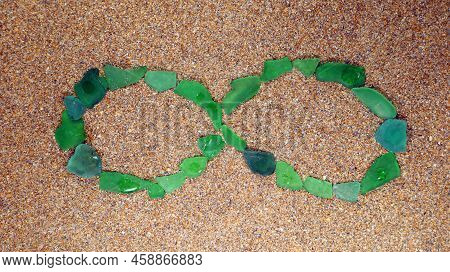 Green Sea Glass Infility Symbol On The Sand. Beach Mediteranian Sea. Vacation. South Sea. Spain