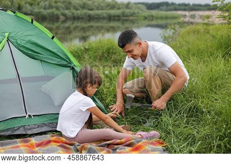 Portrait Of Happy Smiling Man With His Daughter Spending Time Together In Open Air, Setting Up A Ten