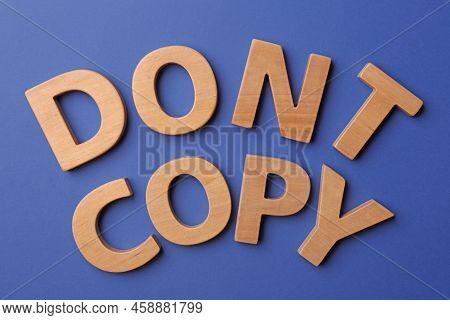 Plagiarism Concept. Phrase Don't Copy Made Of Wooden Letters On Blue Background, Top View