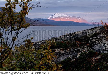 Epic Sunrise Light Illuminating Rocky, Glacier Covered Peak With Dark Cloudy Sky In The Background. 