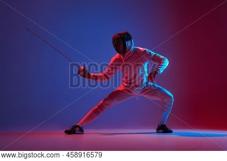 Male Fencer With Smallsword Practicing Fencing Isolated On Purple Background In Neon Light. Sport, E