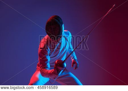 Male Fencer With Smallsword Practicing Fencing Isolated On Purple Background In Neon Light. Sport, E