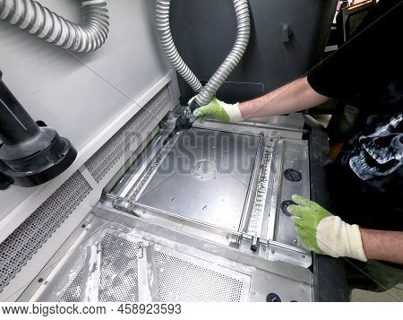 A Male Worker Cleans The Surface Of An Industrial 3d Printer From White Powder With A Vacuum Cleaner