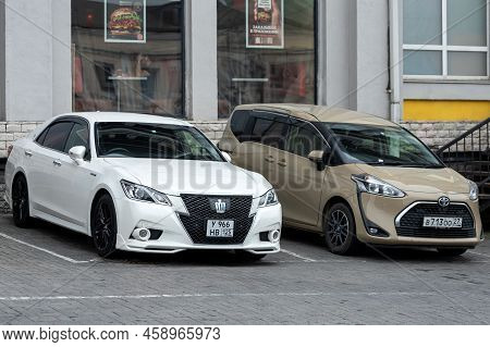 Vladivostok, Russia - July 14, 2022: Silver Toyota Crown And Beeige Toyota Sientais Parking Fast On 