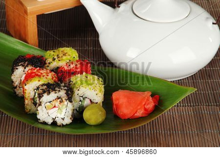 Velsmagende Maki sushi - Roll på grønne blade på grå baggrund
