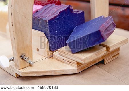 Wooden Device For Cutting Soap Handmade With A Freshly Cut Purple Bar Of Soap. Close Up