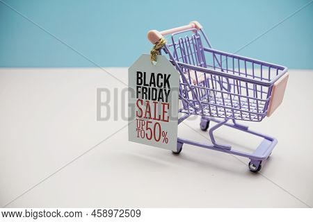 Black Friday Salee 50%  Text Message On Price Tax With Shoppint Trolley Cart On Blue Andp Pink Backg