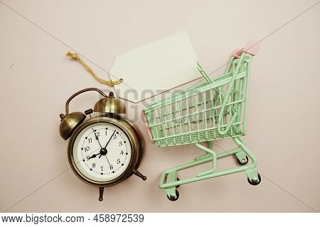 Empty Price Tag With Alarm Clock And Shopping Trolley Cart On Pink Background