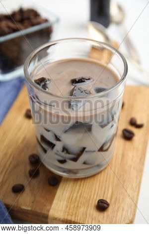 Glass Of Milk With Grass Jelly And Coffee Beans On Wooden Board, Closeup