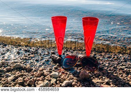 In Summer, Two Red Glasses Of Sparkling Champagne Or Prosecco By Sea  Pebble Beach.