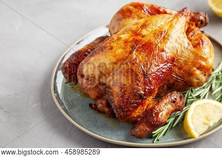 Homemade Lemon And Herb Rotisserie Chicken On A Plate On A Gray Background, Side View.
