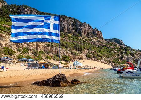 Tsambika, Greece - July 2, 2022: Waving Greek Flag At Tsambika Beach In Rhodes Island In Greece