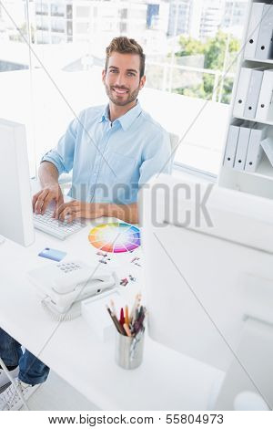 Portrait of a smiling casual male photo editor using computer in the office