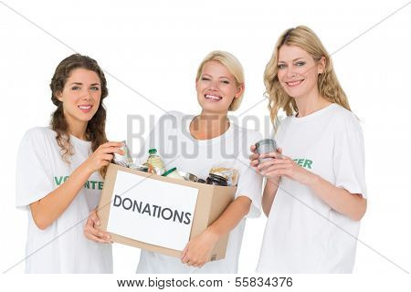 Portrait of three smiling young women with donation box over white background