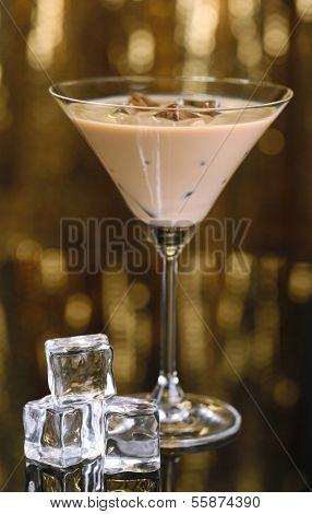 Baileys liqueur in glass on golden background