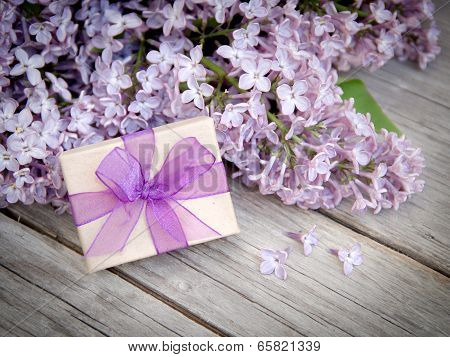 Gift Box With Purple Bow And Lilac On Wood