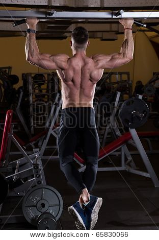 Muscular Young Man Doing Pull Ups (Chin-Ups) in the Gym.