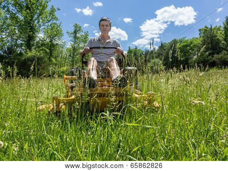 Senior Man On Zero Turn Lawnmower In Meadow