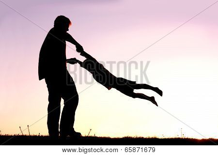 Silhouette Of Father Playing With Child Outside At Sunset