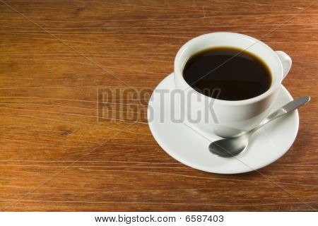 CoffeeCup s kávou v něm na dřevěný stůl