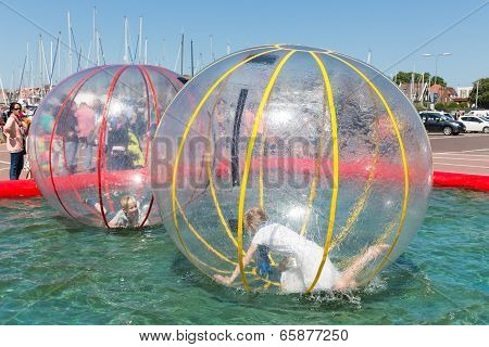 Children Have Fun Inside Plastic Balloons On The Water During A Fishing Fare