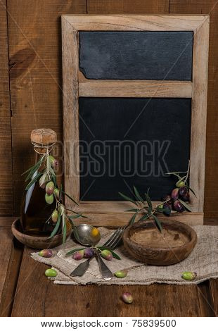 Olive Table Setting With Wooden Bowls, Gray Textile Napkin And Branch Of Olive On Old Wooden Table