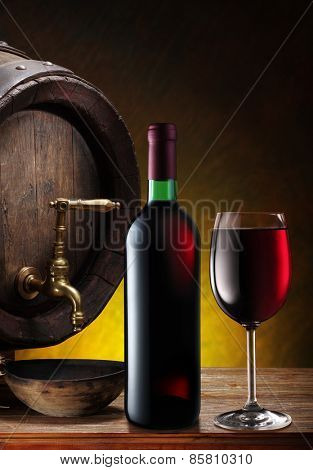 Still-life with glass of wine, bottle and barrel on the table in the cellar.