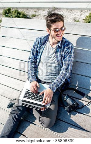 Young photographer with laptop and photo camera