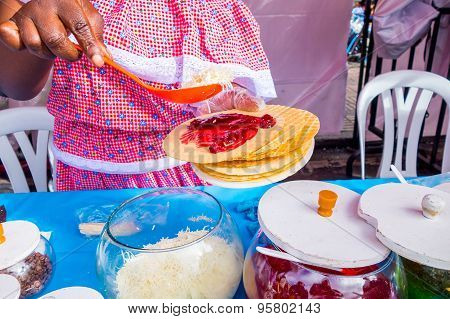 Closeup traditional Colombian streetsnack oblea being prepared adding white sauce with top of jam an