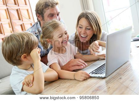 Parents with kids at home using laptop computer