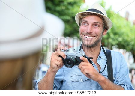 Trendy guy with hat taking picture of woman with vintage camera