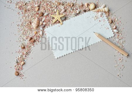 Sea shells, pink sand and invitation card with a pencil on a paper background