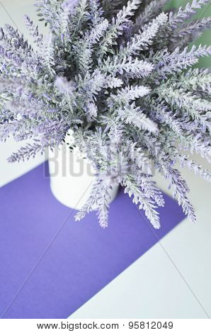 A lavender bouquet in a vase on a white violet background