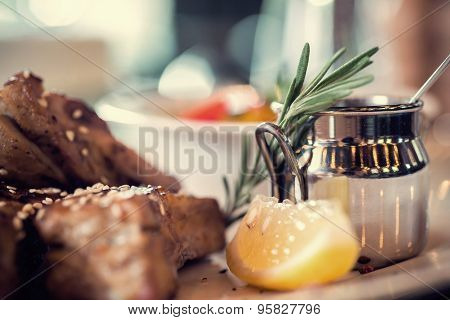 Close up of grilled pork ribs with lemon, sauce and rosmary. Selective Focus