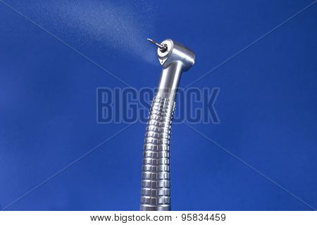 Dental turbine with spray and blue background