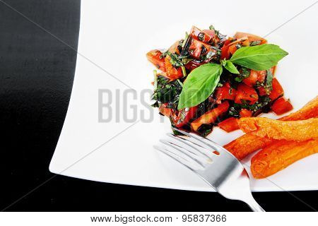 vegetable salad : cherry tomatoes and basil with sweet baked potato served on white plate with sauceboat full blask soy sauce on wood
