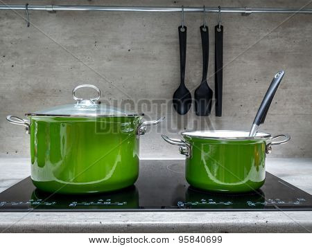 Two green enamel stewpots on black induction cooker